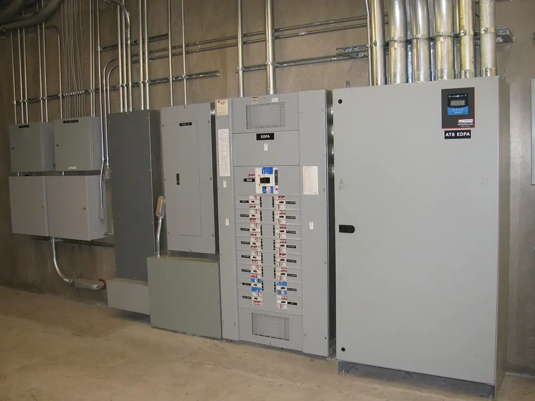 Commercial automatic transfer switch cabinet beside electrical distribution panels